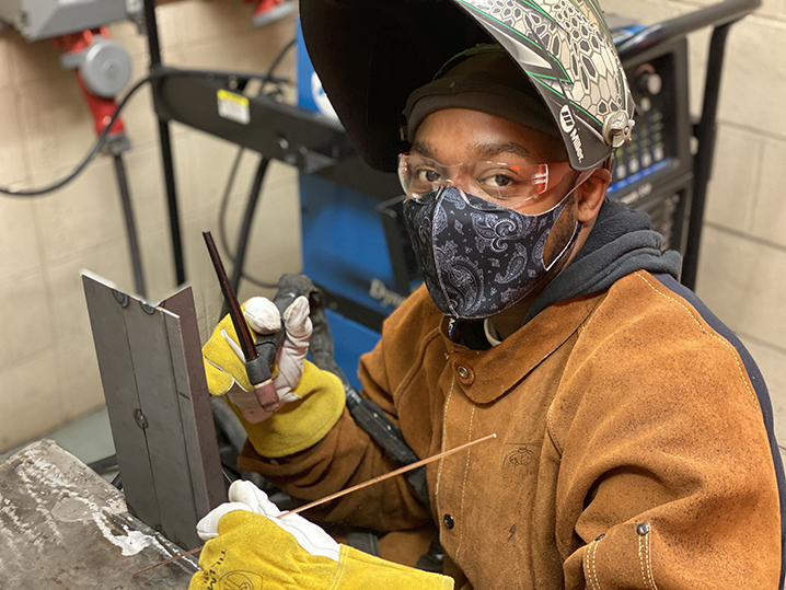 Shawn Babbitt in the welding lab, pictured with safety goggles and welding helmet