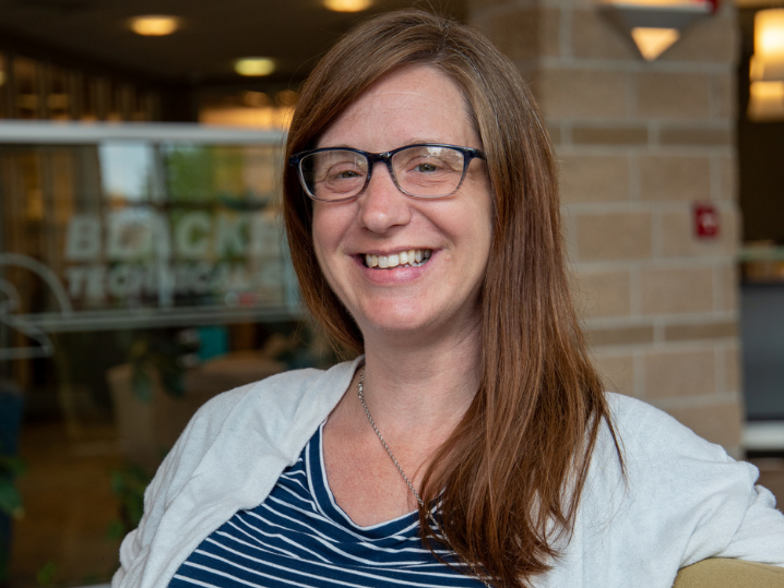 Administrative Assistant Bertha smiling in front lobby of Central Campus