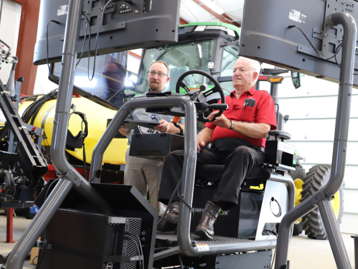 Wayne Albertson using tractor simulator next to Dusty Williams