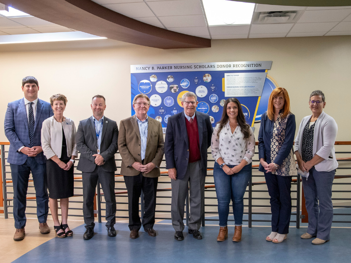 group of leading donors, college leadership, and student recipient in front of Nancy B. Parker Nursing Scholars donor wall