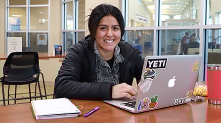 Student with laptop open smiling at camera