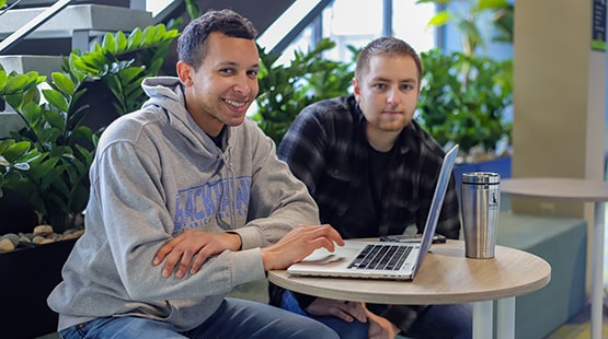 Students using a laptop in the commons area