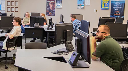 Students sitting at computers listening to instructor in classroom