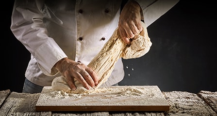 Baker or chef stretching a portion of raw dough