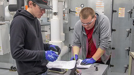 Two students writing in a manufacturing space environment
