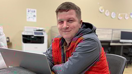 Male student on a laptop smiling at the camera