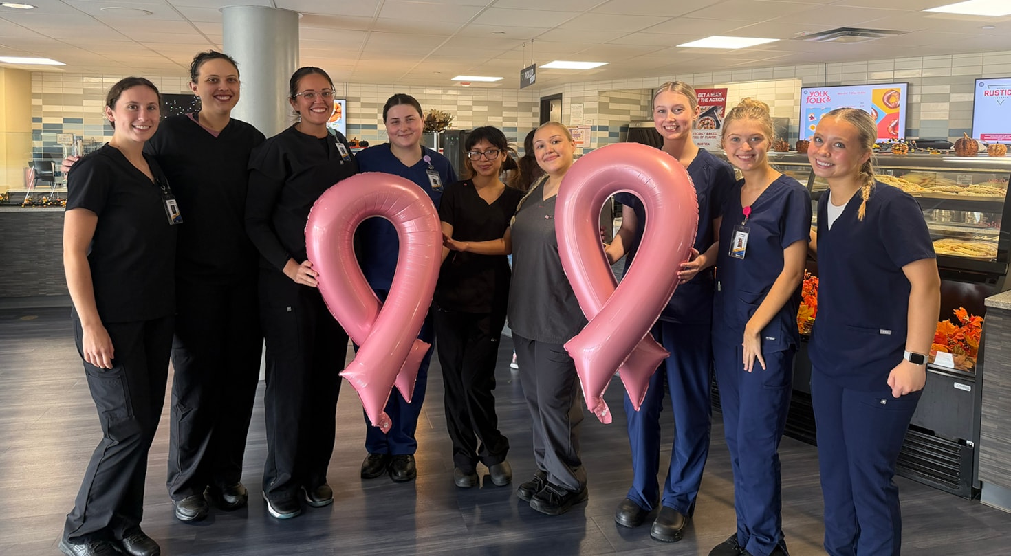 Group of students posing with some breast cancer awareness balloons