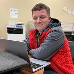 Male student at laptop smiling at the camera