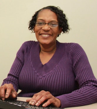 Woman at keyboard smiling at the camera