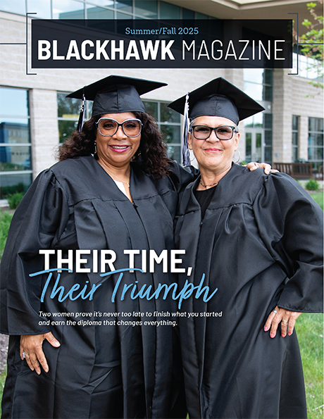 Two graduates in caps and gowns posing outside of Blackhawk's Beloit-Janesville Campus