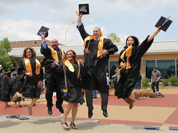 group of graduates in caps and gowns jumping outside